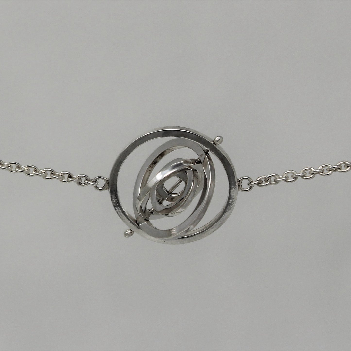 Recycled silver kinetic choker with 5 concentric circle rings spinning on central pin attached to trace chain on each side
