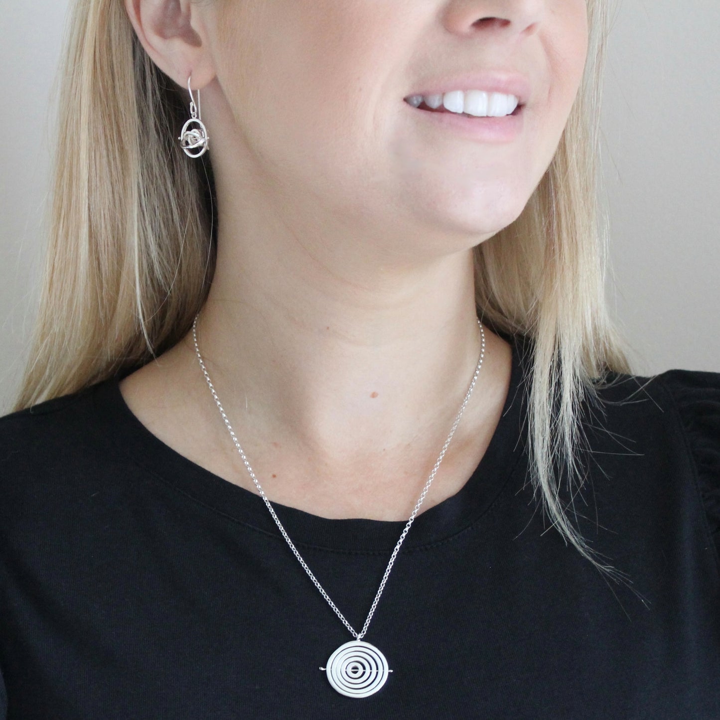 Model wearing handmade sterling silver 1.4cm wide dangly earrings on earwire hook with 2.9cm drop & matching kinetic necklace