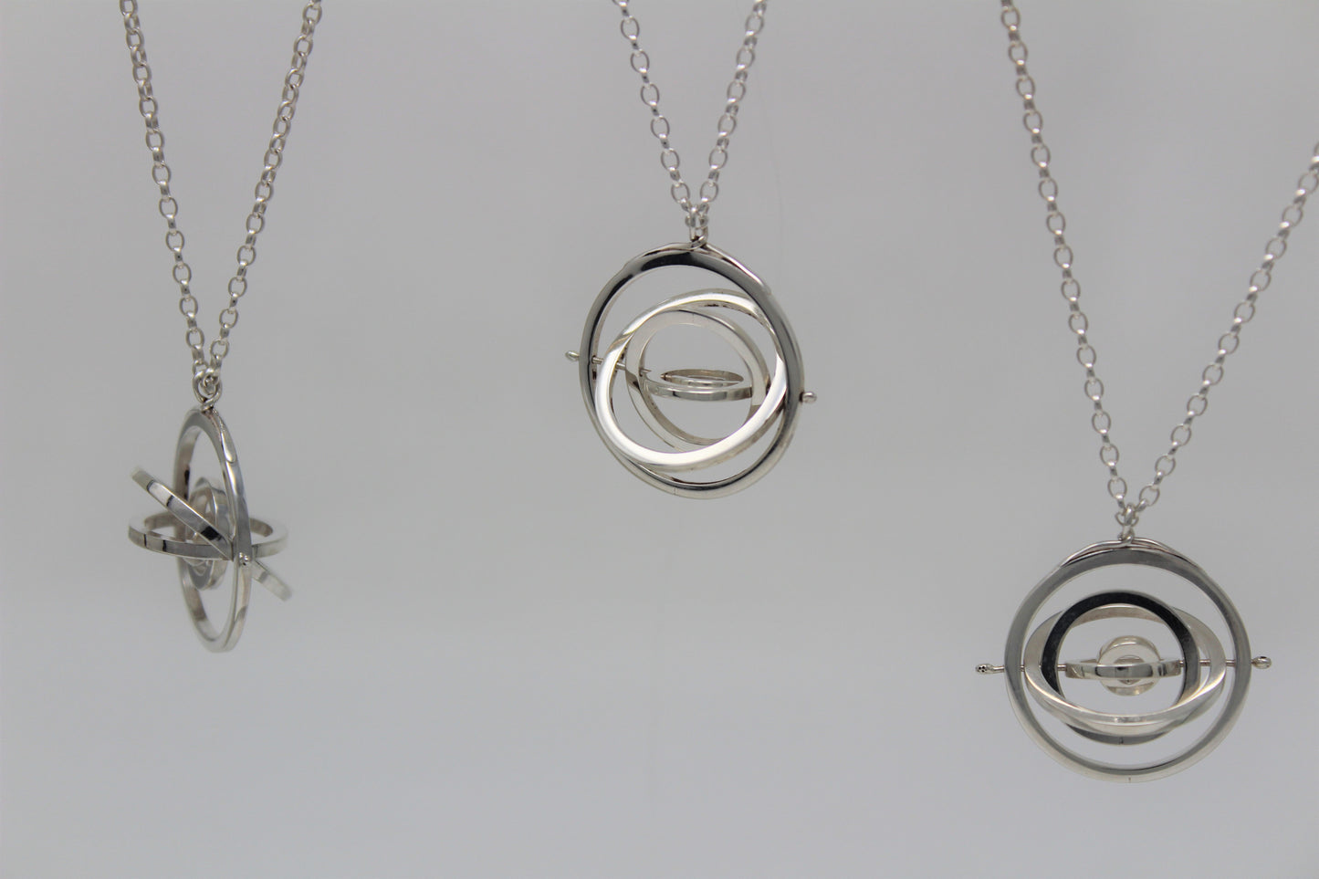 3 sterling silver 2.2cm wide kinetic necklaces each have 5 concentric rings spinning on central pin hanging on belcher chains