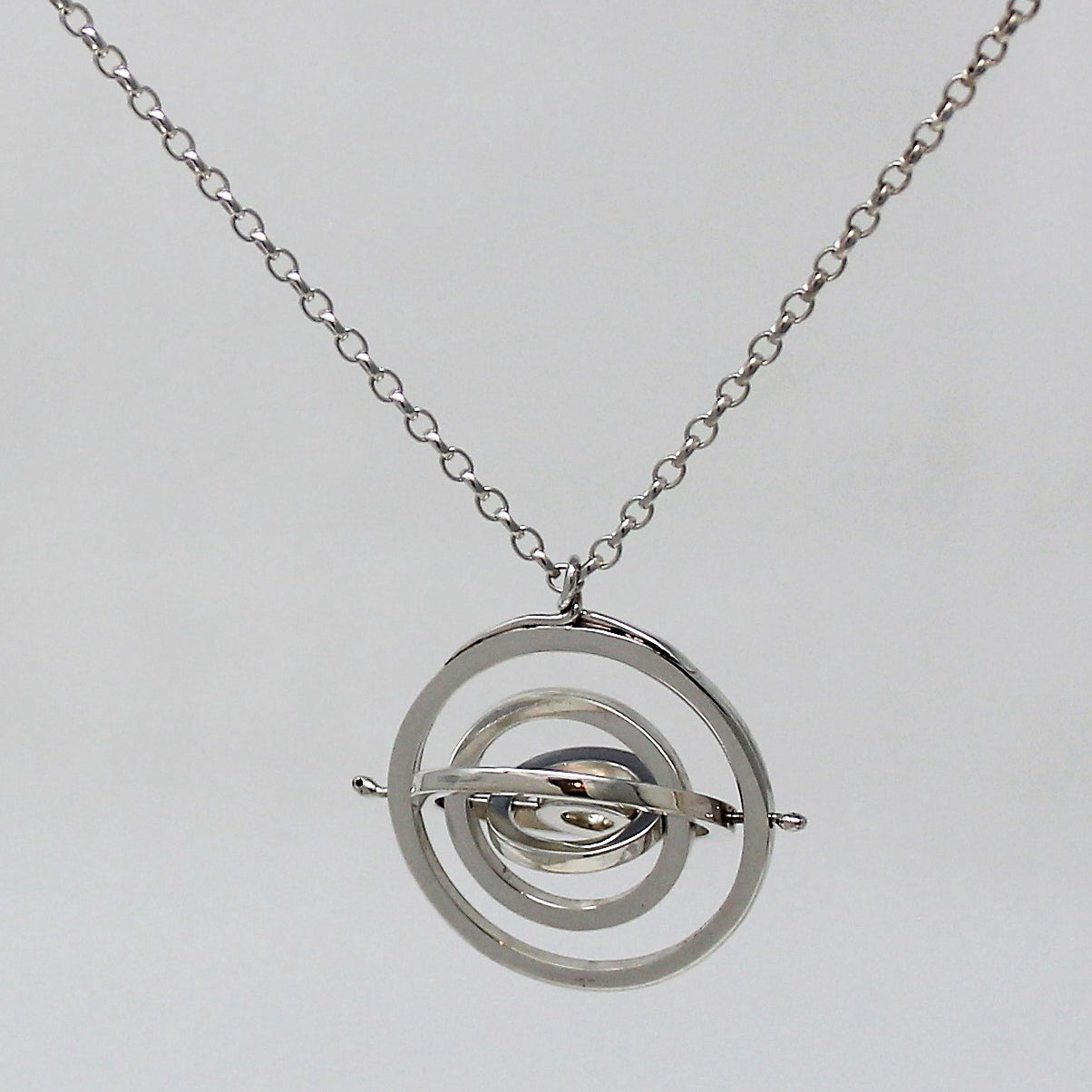 Recycled silver 2.2cm wide kinetic necklace with 5 concentric circle rings spinning on central pin hanging from belcher chain