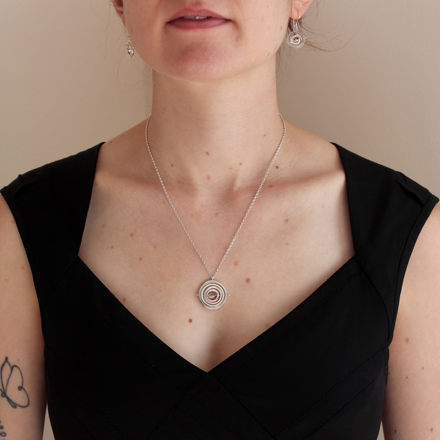 Model wearing handmade sterling silver 2.2cm wide kinetic necklace on 18”/45cm belcher chain hanging in centre of upper chest