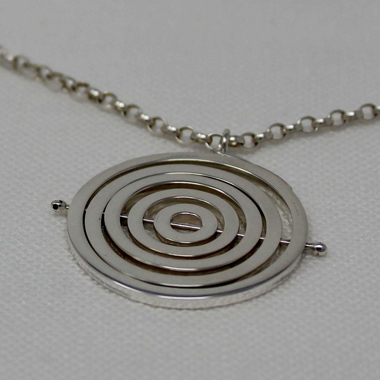 Hallmarked silver kinetic pendant with 5 concentric recycled square wire rings held by central pin, with chunky belcher chain