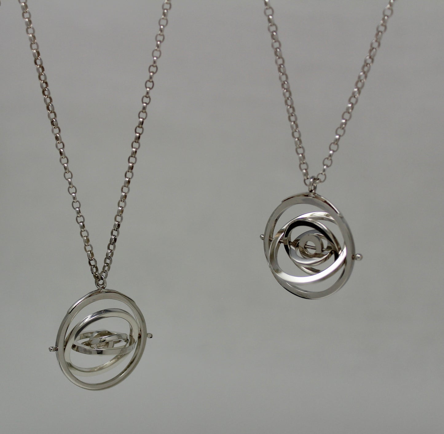 Two hallmarked silver 3cm wide kinetic pendants with 5 concentric rings spinning on central pin, with chunky bencher chain