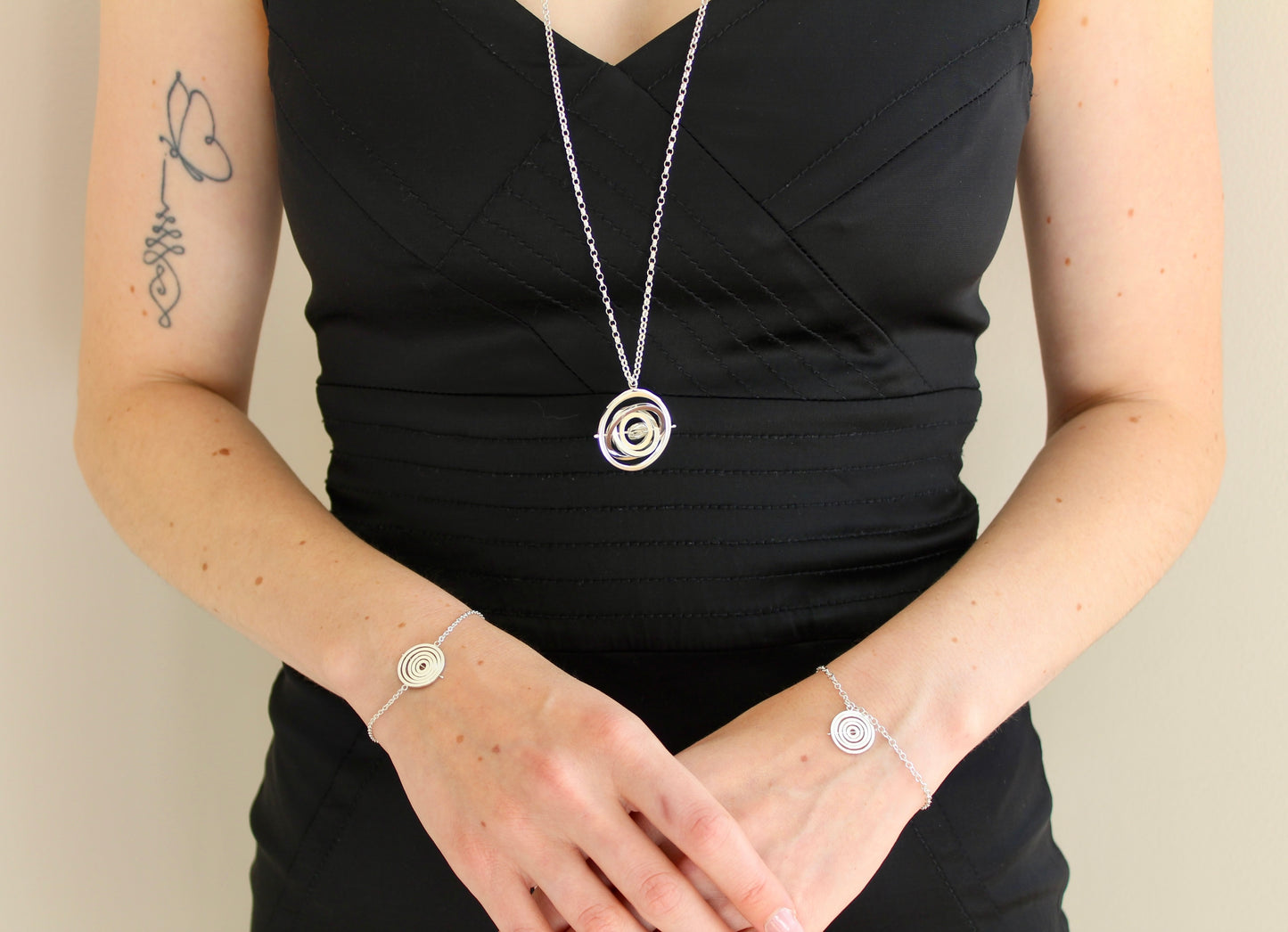 Model wearing hallmarked silver kinetic pendant on 80cm chunky belcher chain hanging below bustline & matching dainty bracelets