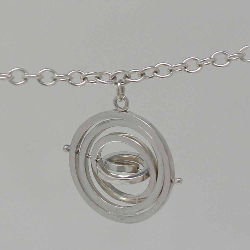 Recycled silver kinetic bracelet charm 1.5cm wide with 5 concentric rings around central pin hanging from delicate trace chain