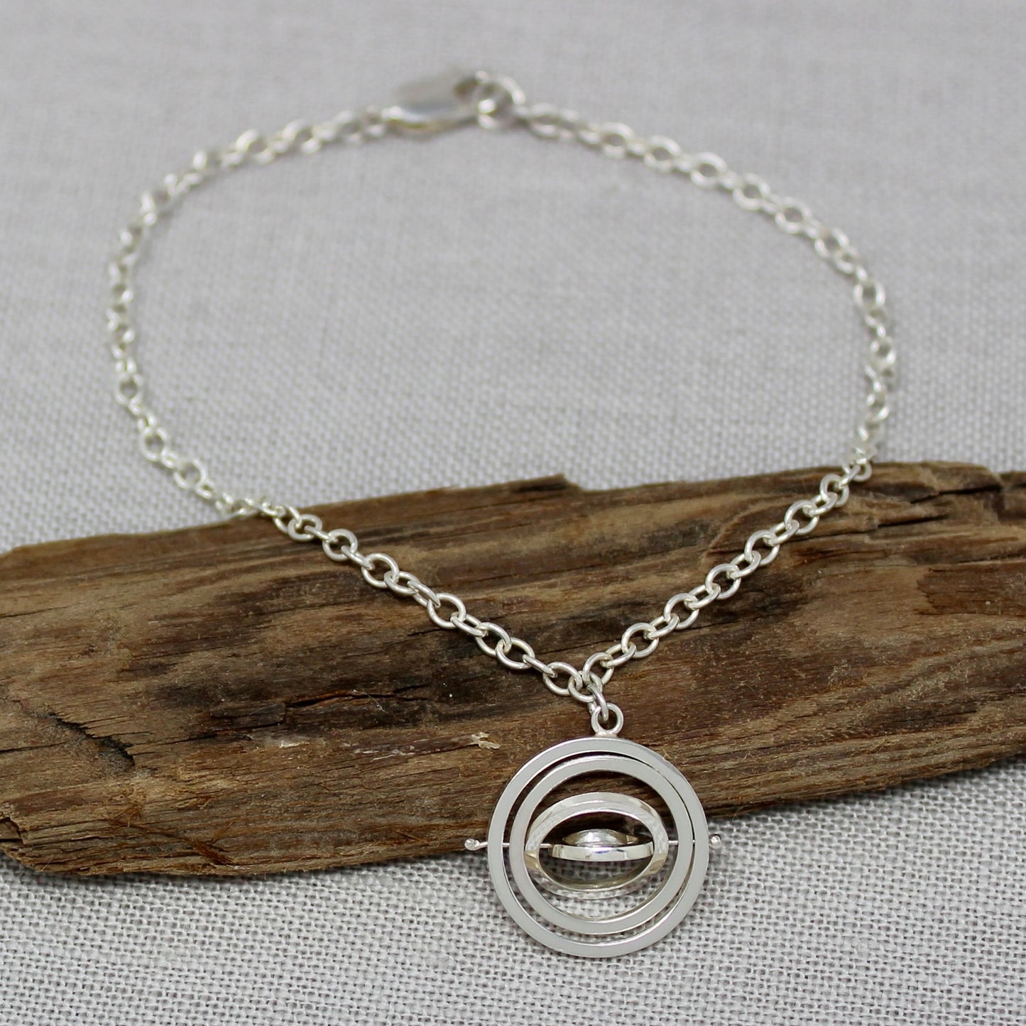 Handmade recycled silver kinetic charm bracelet, trace chain with concentric rings pivoting on central pin with lobster clasp