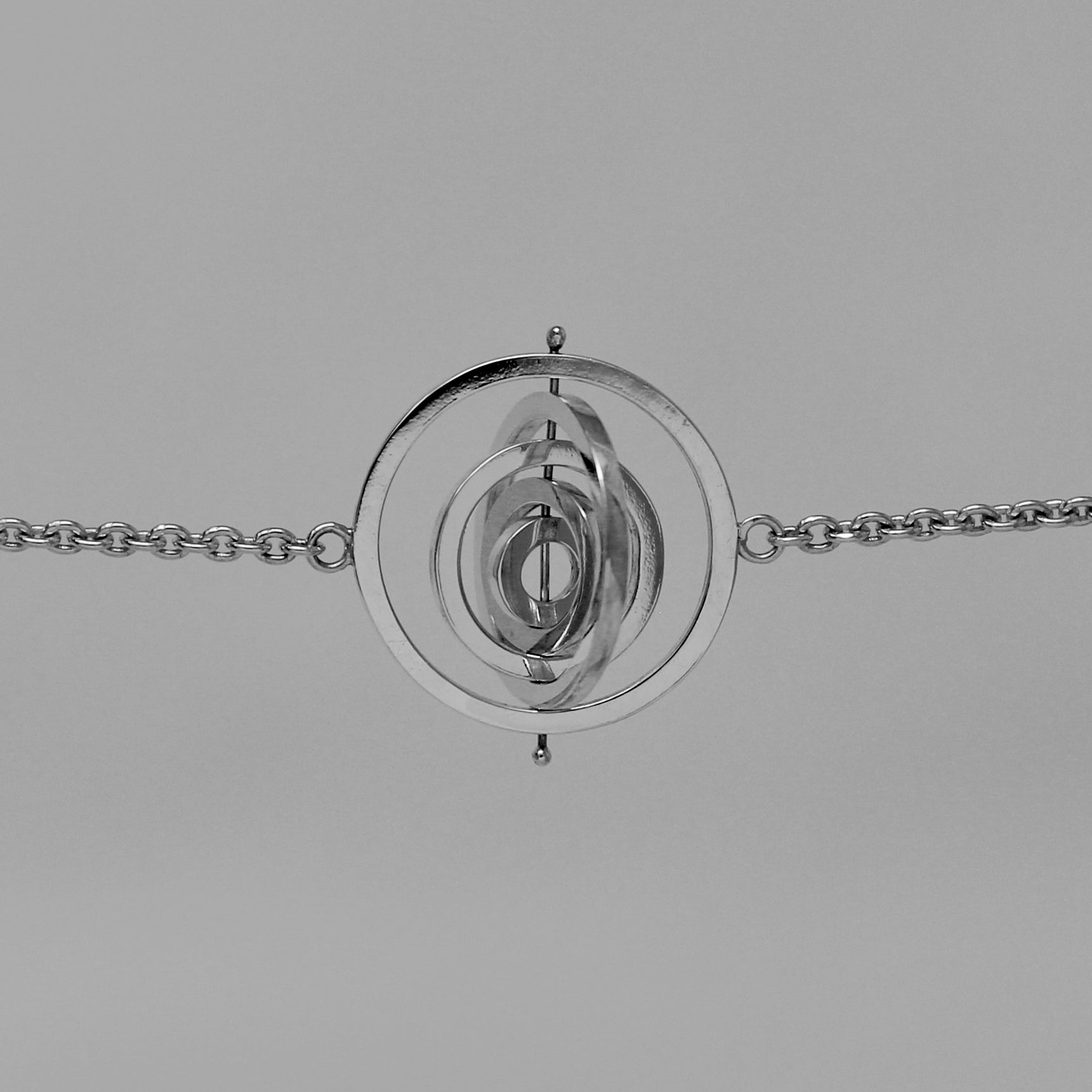 Recycled silver kinetic bracelet with 5 concentric circle rings spinning on central pin attached to trace chain on each side